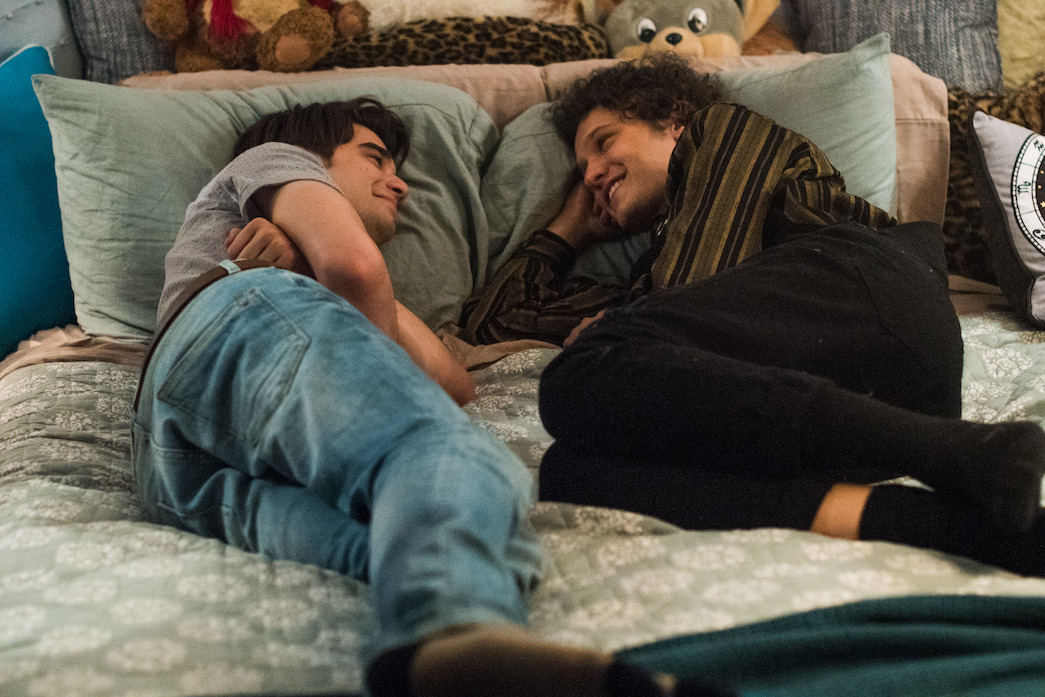 Daniel Doheny in rolul lui Alex Truelove si Antonio Marziale in rolul lui Elliot stateau intinsi pe un pat impreuna zambind in „Alex Strangelove”.